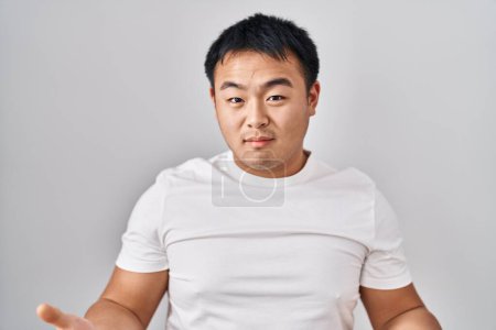 Photo for Young chinese man standing over white background clueless and confused with open arms, no idea concept. - Royalty Free Image