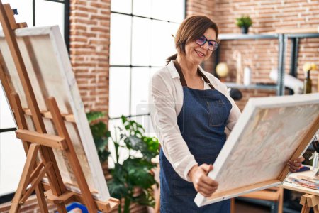 Foto de Middle age woman artist smiling confident looking draw at art studio - Imagen libre de derechos