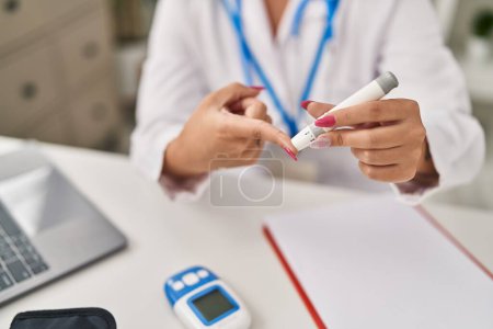 Téléchargez les photos : Jeune belle femme hispanique médecin mesurant le glucose à la clinique - en image libre de droit