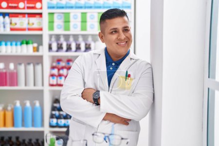 Photo for Young latin man pharmacist smiling confident standing with arms crossed gesture at pharmacy - Royalty Free Image