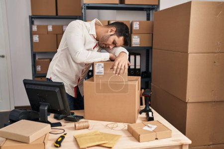 Photo for Young hispanic man e-commerce business worker tired leaning on packages at office - Royalty Free Image