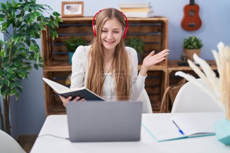Téléchargez les photos : Jeune femme caucasienne étudiant à l'aide d'un ordinateur portable célébrant la réalisation avec sourire heureux et expression gagnante avec la main levée - en image libre de droit