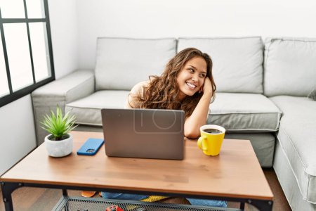 Photo for Young beautiful hispanic woman using laptop sitting on floor at home - Royalty Free Image