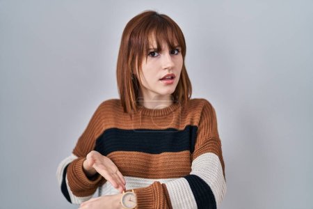 Téléchargez les photos : Young beautiful woman wearing striped sweater over isolated background in hurry pointing to watch time, impatience, upset and angry for deadline delay - en image libre de droit