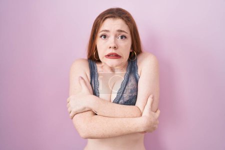 Photo for Redhead woman wearing lingerie over pink background shaking and freezing for winter cold with sad and shock expression on face - Royalty Free Image