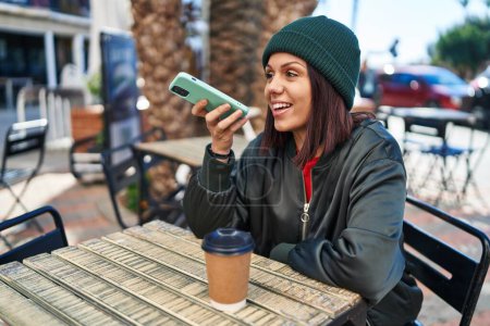 Téléchargez les photos : Jeune belle femme hispanique parlant sur smartphone boire du café à la terrasse du café - en image libre de droit
