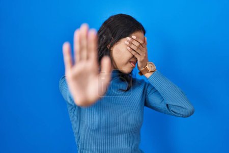 Téléchargez les photos : Young brazilian woman standing over blue isolated background covering eyes with hands and doing stop gesture with sad and fear expression. embarrassed and negative concept. - en image libre de droit
