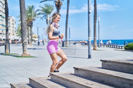 Photo for Young blonde woman wearing sportswear running at seaside - Royalty Free Image