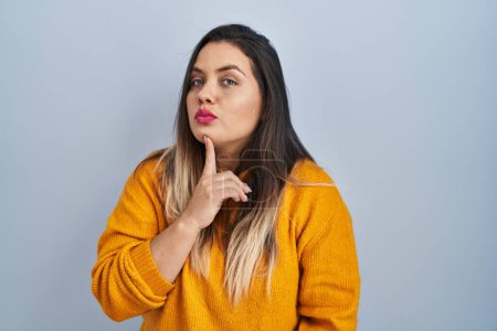 Photo for Young hispanic woman standing over isolated background thinking concentrated about doubt with finger on chin and looking up wondering - Royalty Free Image