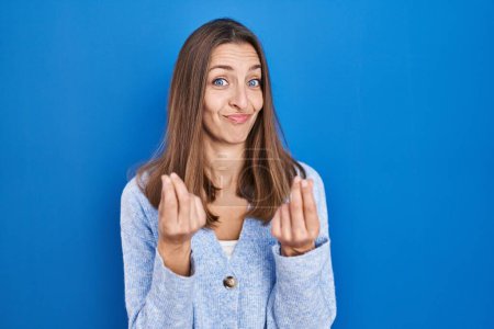 Photo for Young woman standing over blue background doing money gesture with hands, asking for salary payment, millionaire business - Royalty Free Image
