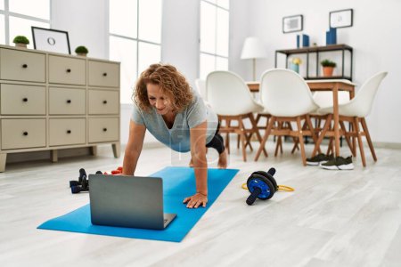 Photo for Middle age caucasian woman smiling confident using laptop  stretching at home - Royalty Free Image