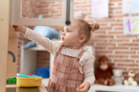 Téléchargez les photos : Adorable fille caucasienne jouer avec jouer cuisine debout à la maternelle - en image libre de droit