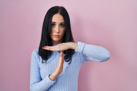Photo for Hispanic woman standing over pink background doing time out gesture with hands, frustrated and serious face - Royalty Free Image