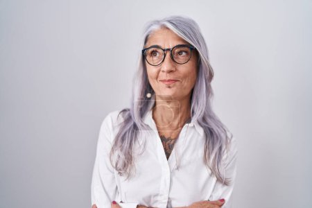 Photo for Middle age woman with tattoos wearing glasses standing over white background smiling looking to the side and staring away thinking. - Royalty Free Image