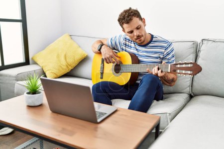 Photo for Young hispanic man smiling confident playing online guitar concert at home - Royalty Free Image