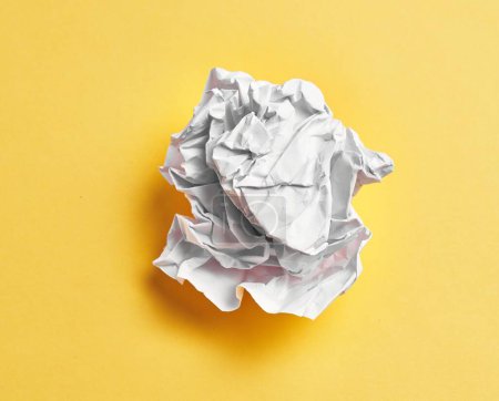 Foto de One white crumpled paper ball over isolated yellow background - Imagen libre de derechos