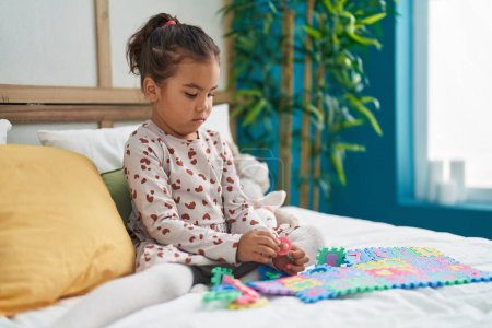 Téléchargez les photos : Adorable fille hispanique jouant jeu de mathématiques assis sur le lit dans la chambre - en image libre de droit