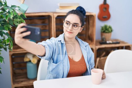 Photo for Young caucasian woman drinking coffee make selfie by smartphone at home - Royalty Free Image