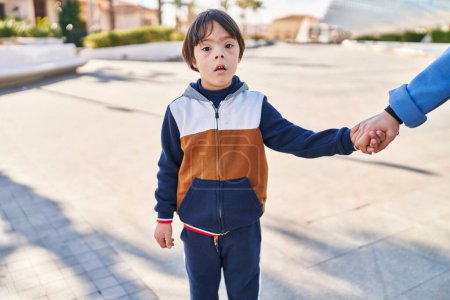 Téléchargez les photos : Enfant trisomique debout avec une expression détendue au parc - en image libre de droit