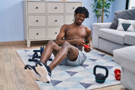 Téléchargez les photos : Afro-américain homme souriant entraînement confiant abs exercice à la maison - en image libre de droit