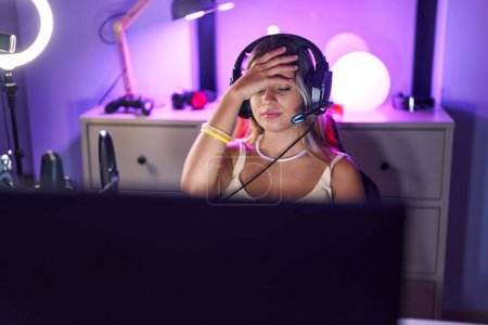 Téléchargez les photos : Jeune femme blonde streamer souligné en utilisant l'ordinateur à la salle de jeux - en image libre de droit