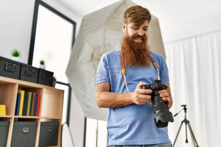 Photo for Young redhead man photographer using professional camera at photograpy studio - Royalty Free Image