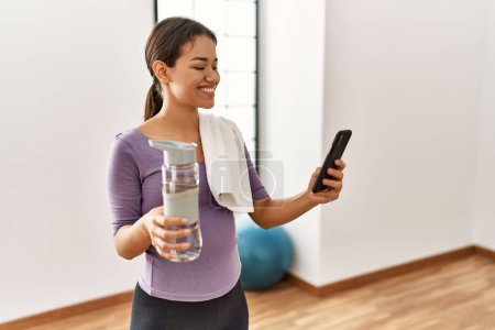 Photo for Young latin woman smiling confident using smartphone at sport center - Royalty Free Image
