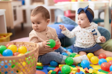 Photo for Two toddlers playing with balls sitting on floor at kindergarten - Royalty Free Image
