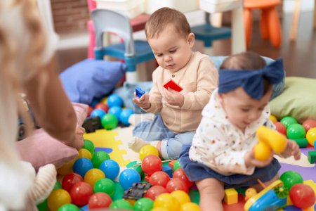 Foto de Dos niños pequeños jugando con juguetes sentados en el suelo en el jardín de infantes - Imagen libre de derechos