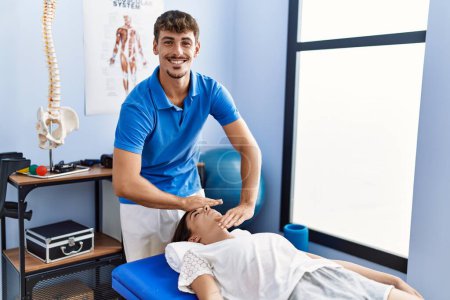 Photo for Man and woman wearing physiotherpy uniform having reiki therapy session at clinic - Royalty Free Image