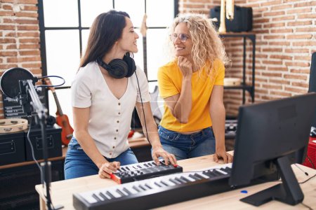 Photo for Two women musicians composing song using keyboard at music studio - Royalty Free Image