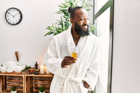 Photo for Young african american man smiling confident drinking champagne at beauty center - Royalty Free Image