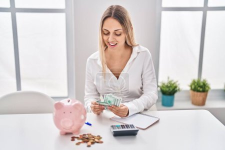Photo for Young woman smiling confident counting dollars at home - Royalty Free Image