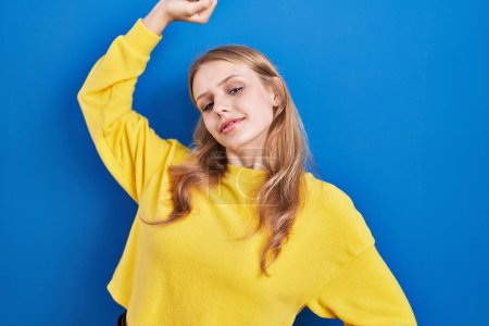 Photo for Young caucasian woman standing over blue background stretching back, tired and relaxed, sleepy and yawning for early morning - Royalty Free Image
