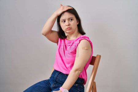 Photo for Woman with down syndrome wearing band aid for vaccine injection stressed and frustrated with hand on head, surprised and angry face - Royalty Free Image