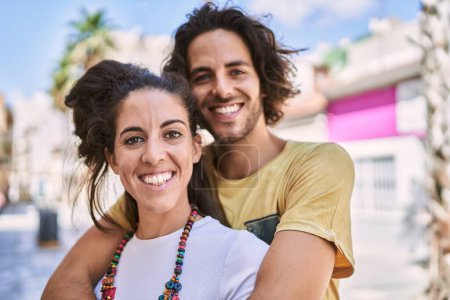 Téléchargez les photos : Homme et femme couple souriant confiant s'embrasser dans la rue - en image libre de droit