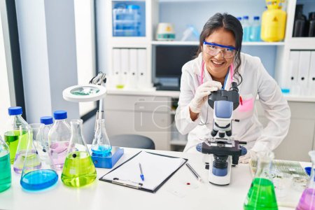 Téléchargez les photos : Jeune Chinoise portant un uniforme de scientifique au microscope en laboratoire - en image libre de droit