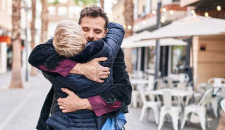 Téléchargez les photos : Mère et fils souriant confiants s'embrassant dans la rue - en image libre de droit