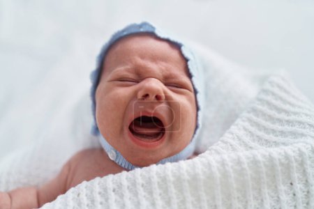 Foto de Adorable bebé caucásico llorando en brazos de madre en el dormitorio - Imagen libre de derechos