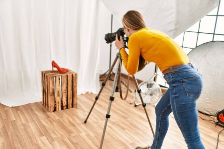 Téléchargez les photos : Young caucasian woman photographer making photo to high heel shoe at photography studio - en image libre de droit