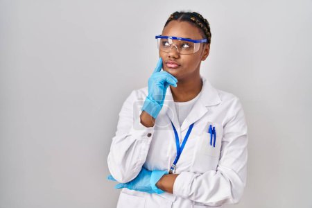 Photo for African american woman with braids wearing scientist robe serious face thinking about question with hand on chin, thoughtful about confusing idea - Royalty Free Image