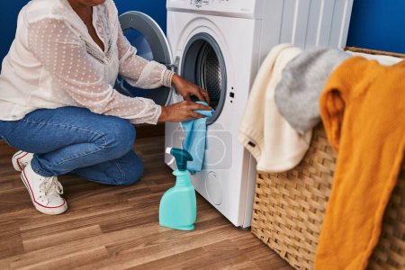 Téléchargez les photos : Femme d'âge moyen nettoyage machine à laver à la buanderie - en image libre de droit