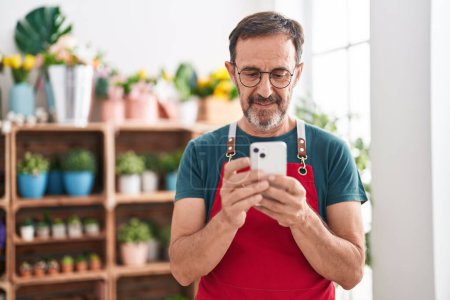 Photo for Middle age man florist smiling confident using smartphone at florist - Royalty Free Image