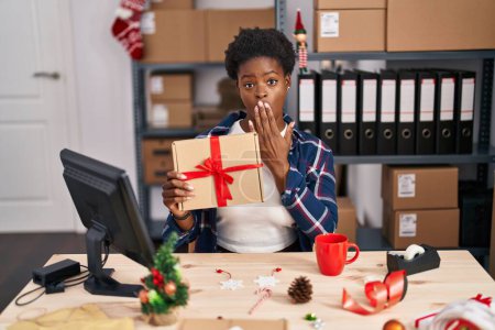 Photo for African american woman standing by manikin at small business on christmas covering mouth with hand, shocked and afraid for mistake. surprised expression - Royalty Free Image