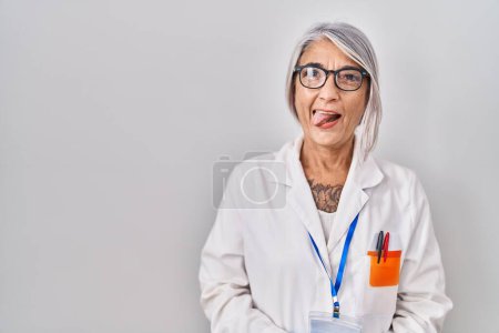 Photo for Middle age woman with grey hair wearing scientist robe sticking tongue out happy with funny expression. emotion concept. - Royalty Free Image