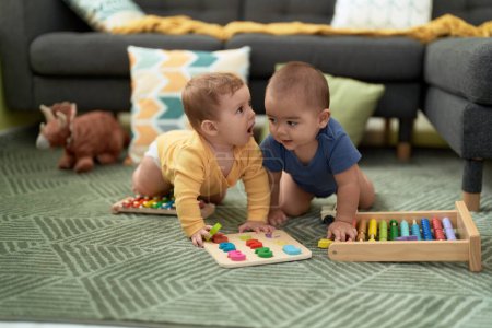 Foto de Dos niños pequeños jugando con juguetes matemáticos sentados en el suelo en casa - Imagen libre de derechos
