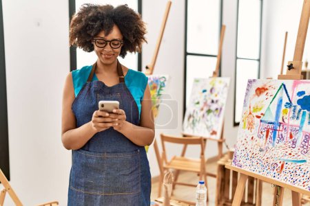 Photo for Young african american woman smiling confident using smartphone at art studio - Royalty Free Image