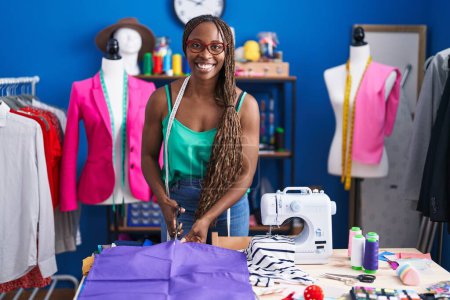 Foto de African american woman tailor smiling confident cutting cloth at atelier - Imagen libre de derechos