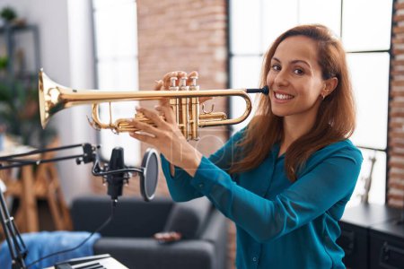 Foto de Young woman musician playing trumpet at music studio - Imagen libre de derechos