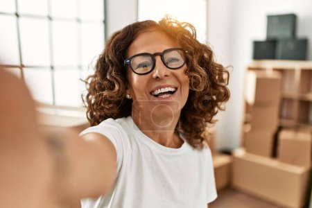 Photo for Middle age hispanic woman smiling confident make selfie by the camera at new home - Royalty Free Image